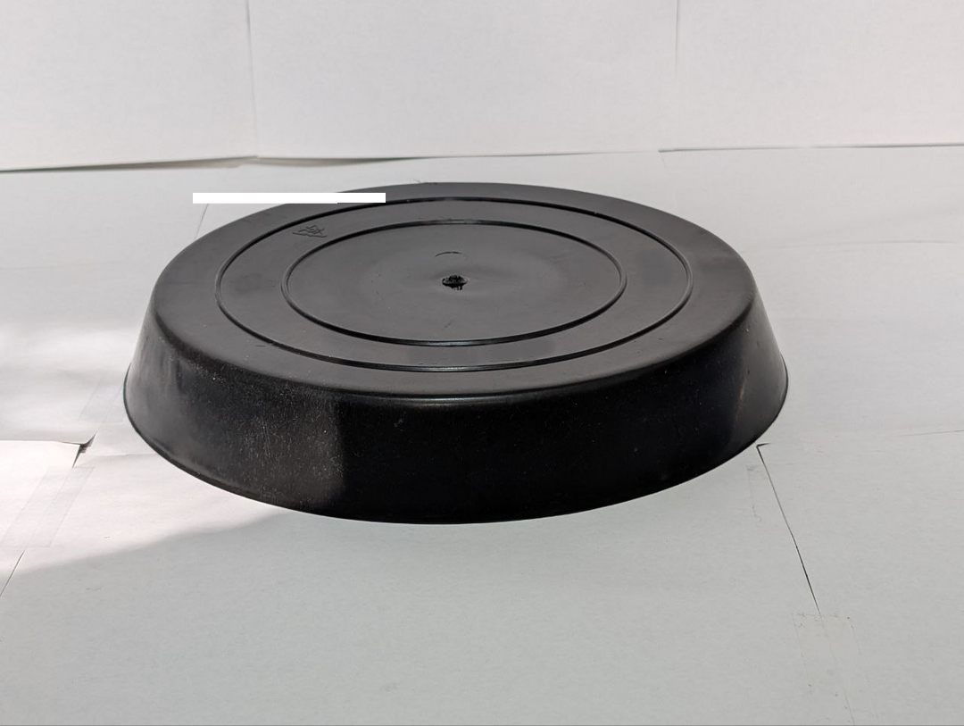 Black round planter on a white tiled floor