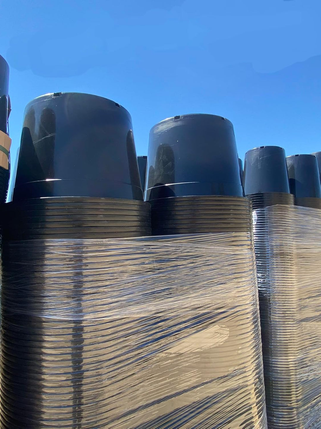Stack of 20 gallon black plastic nursery pots with drainage holes